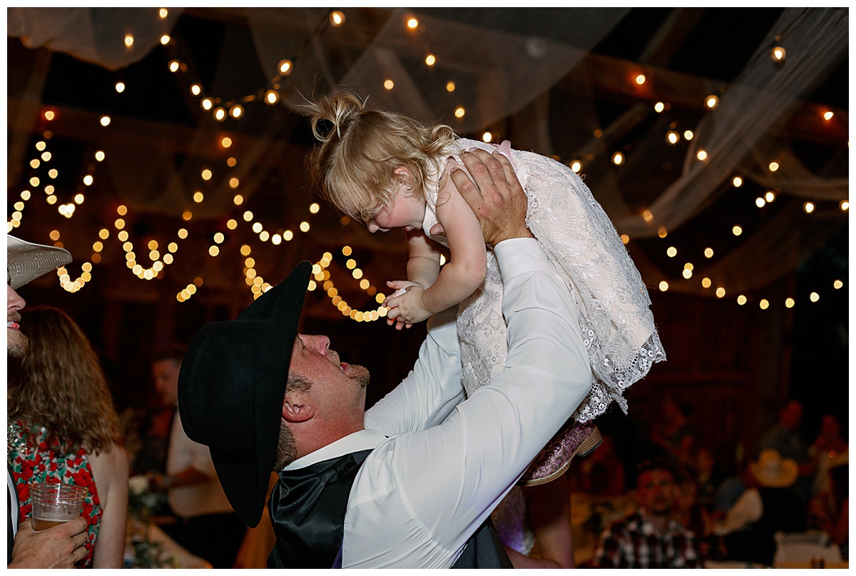 Groom lifting flower girl at reception
